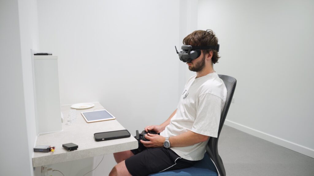 Our Drone Pilot sitting at desk with FPV goggles on and control in hand in Mondelēz International new research facility.