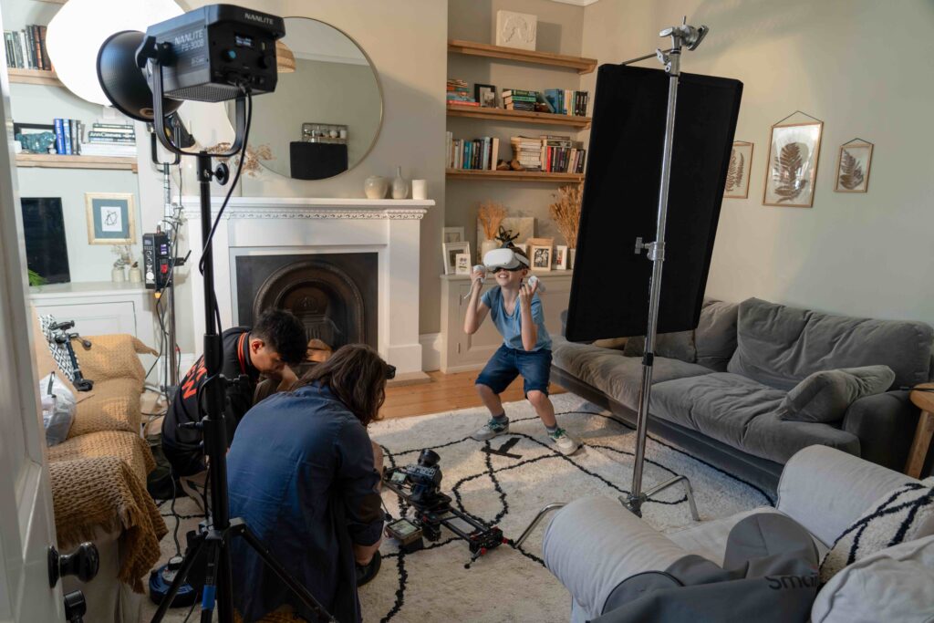 Spark Media film crew with camera at a low angle and filming lights in living room filming boy wearing VR headset for Luceco TV ad