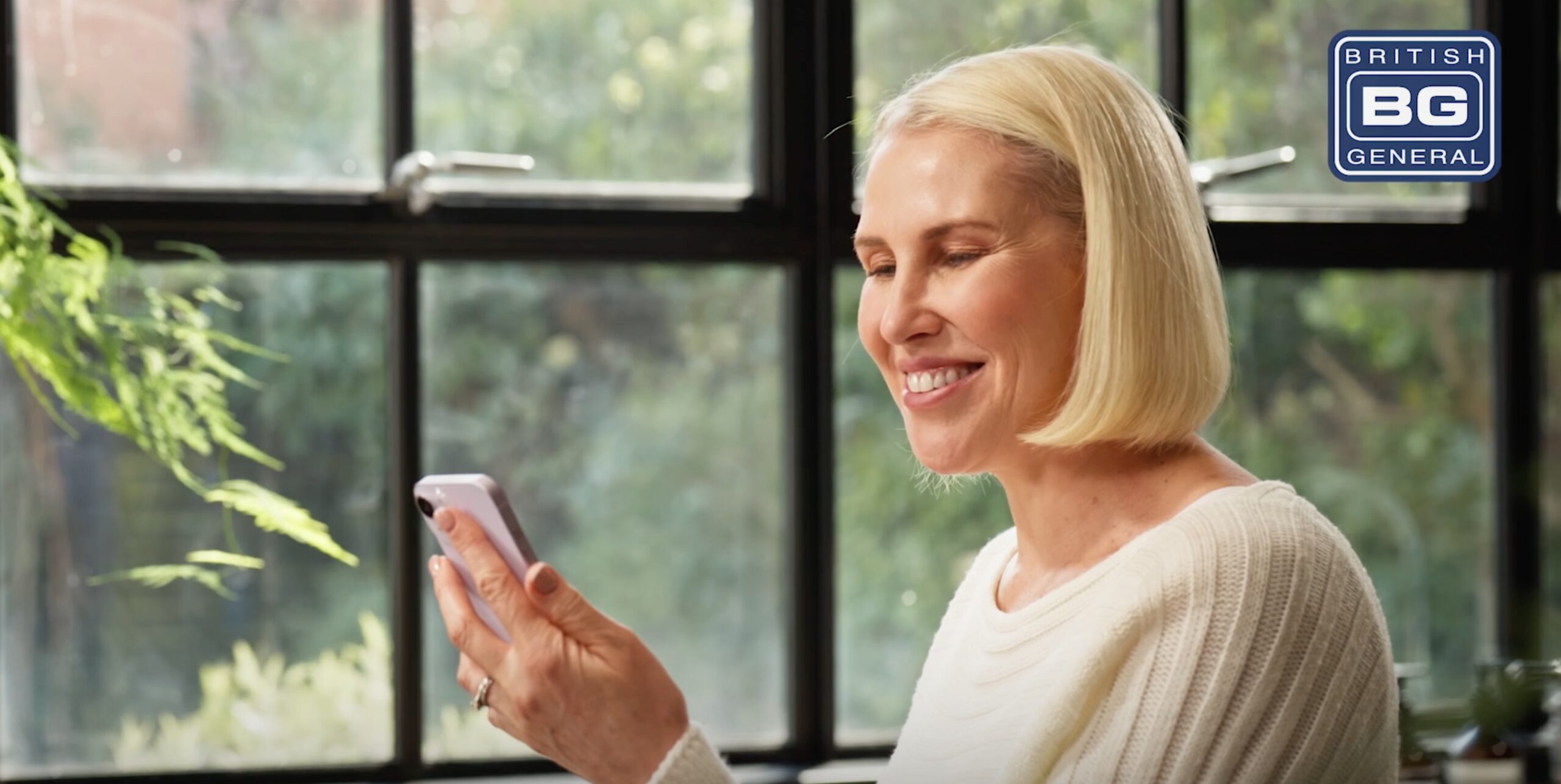 Woman with blonde hair looking at phone in kitchen in Luceco TV ad