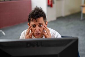 Male actor looks stressed out looking at computer screen.