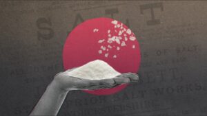 Hand holding a pile of salt. Pink dot in the background.